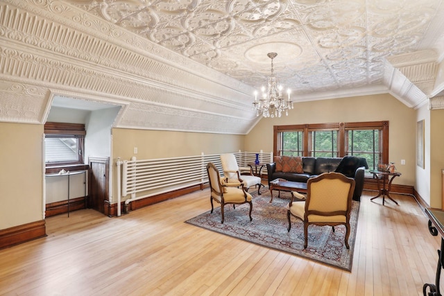 living room featuring hardwood / wood-style flooring, a notable chandelier, lofted ceiling, and crown molding