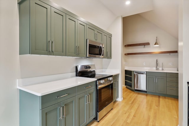 kitchen with lofted ceiling, green cabinets, sink, light hardwood / wood-style flooring, and appliances with stainless steel finishes