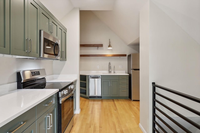 kitchen featuring green cabinets, vaulted ceiling, and appliances with stainless steel finishes