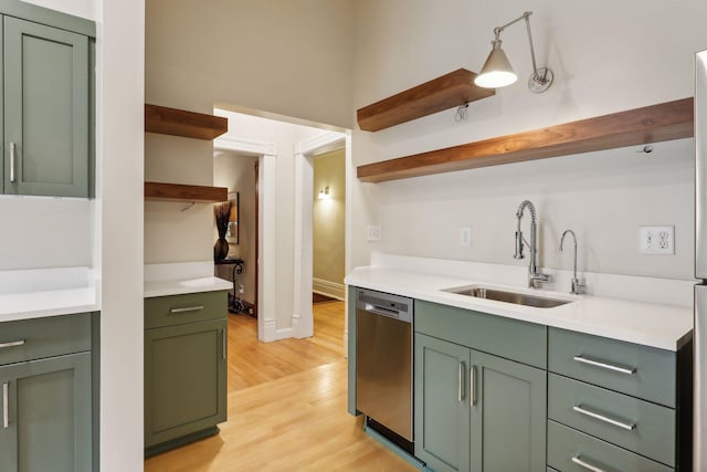 kitchen with dishwasher, green cabinets, sink, hanging light fixtures, and light wood-type flooring