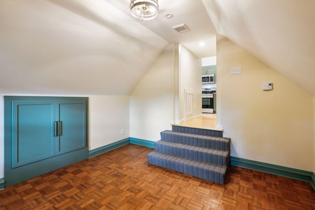 additional living space featuring dark parquet flooring and vaulted ceiling