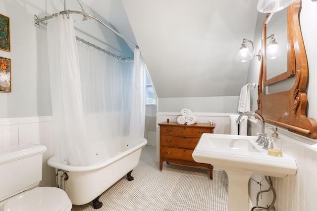 bathroom with a tub to relax in, toilet, and lofted ceiling