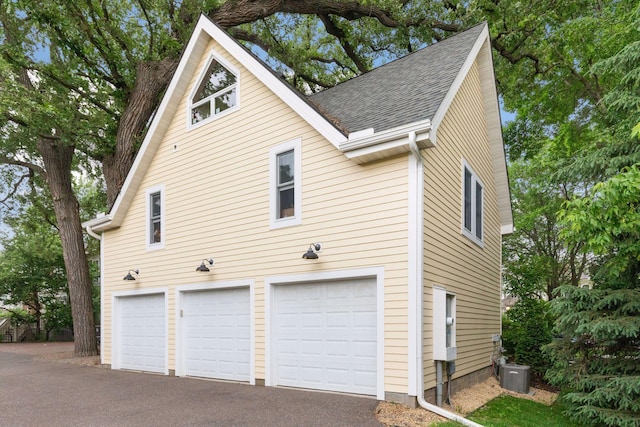 view of side of home with a garage and central AC unit