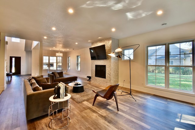 living room with a chandelier, a fireplace, and light hardwood / wood-style floors