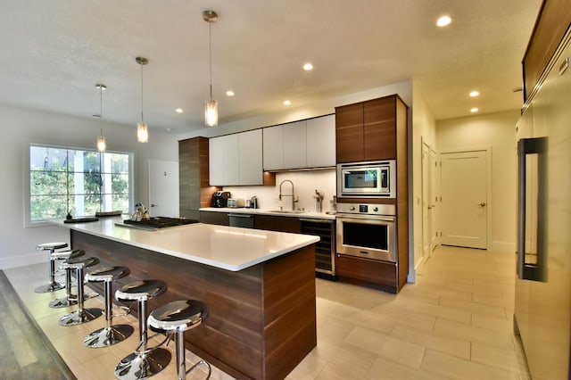 kitchen with hanging light fixtures, a kitchen bar, stainless steel appliances, wine cooler, and a center island