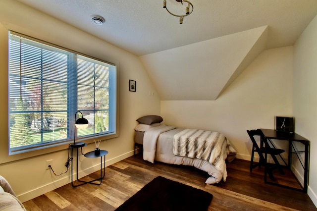 bedroom with dark hardwood / wood-style flooring, vaulted ceiling, and multiple windows