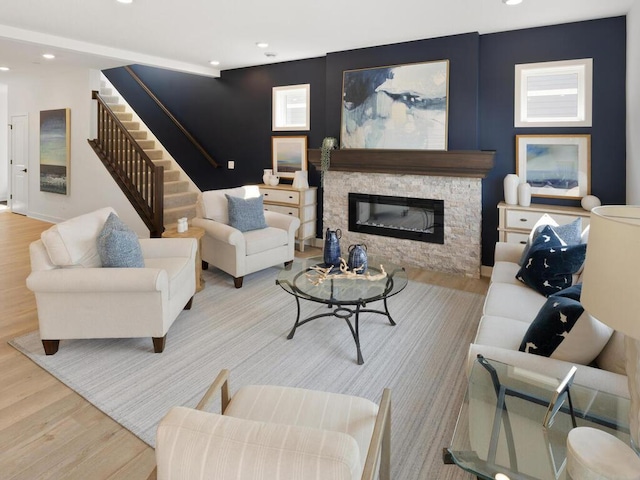 living room with a stone fireplace and light wood-type flooring