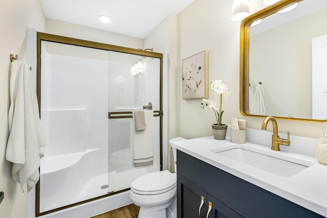 bathroom with hardwood / wood-style floors, vanity, toilet, and a shower with shower door