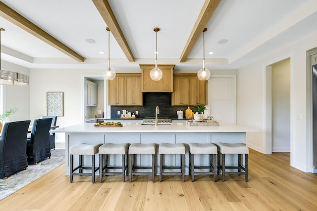 kitchen featuring a spacious island, hanging light fixtures, a breakfast bar area, and light hardwood / wood-style flooring