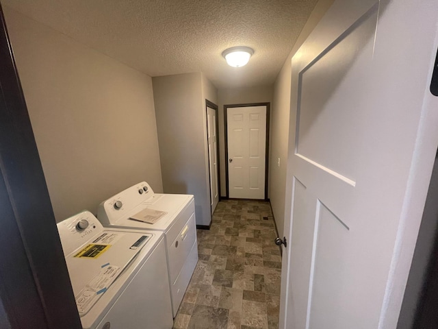 clothes washing area with independent washer and dryer, a textured ceiling, and dark tile flooring