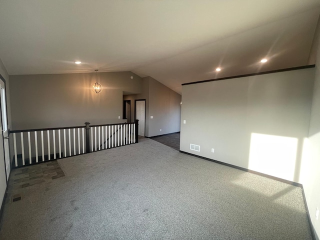 carpeted empty room with vaulted ceiling