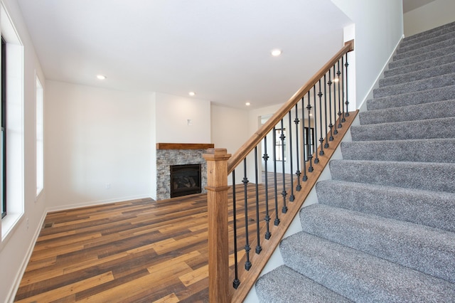 stairway featuring a stone fireplace and dark hardwood / wood-style flooring