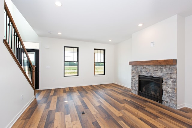 unfurnished living room with a stone fireplace and dark hardwood / wood-style flooring