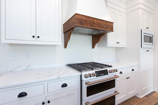 kitchen featuring white cabinetry, stainless steel microwave, and premium range hood