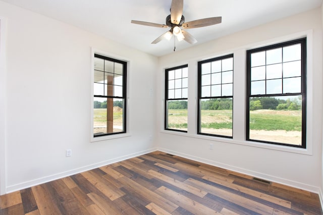 unfurnished room featuring ceiling fan, dark wood-type flooring, and a wealth of natural light