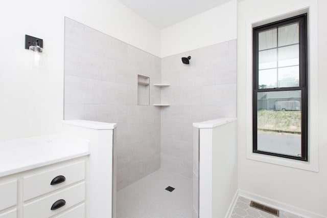 bathroom featuring tile flooring, tiled shower, and vanity