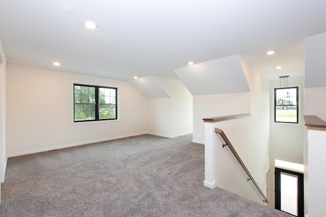 additional living space featuring vaulted ceiling and carpet flooring