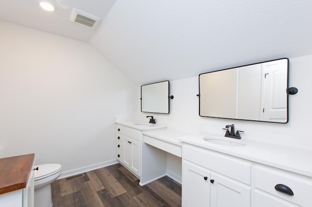 bathroom with hardwood / wood-style floors, toilet, dual vanity, and vaulted ceiling