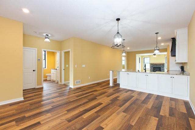 kitchen with decorative light fixtures, white cabinetry, dark wood-type flooring, custom range hood, and light stone counters