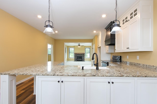 kitchen featuring black range with electric stovetop, ceiling fan, white cabinets, hanging light fixtures, and light stone counters