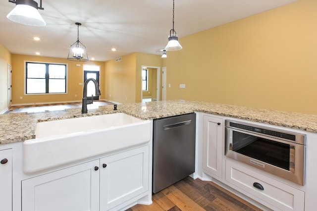 kitchen with pendant lighting, dark hardwood / wood-style floors, white cabinets, and appliances with stainless steel finishes