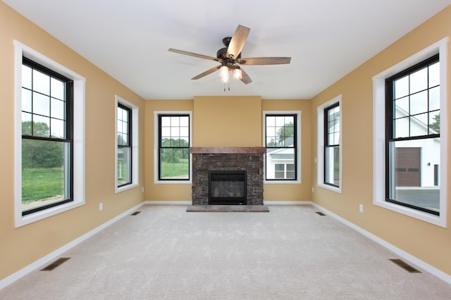 unfurnished living room featuring ceiling fan, a fireplace, and light carpet