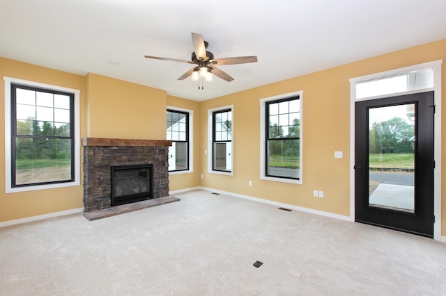 unfurnished living room with light carpet, a healthy amount of sunlight, ceiling fan, and a fireplace