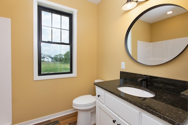 bathroom with hardwood / wood-style floors, toilet, plenty of natural light, and vanity