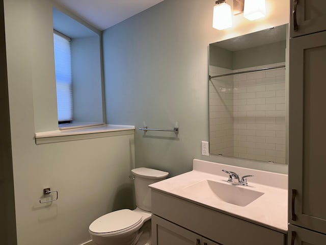 bathroom with vanity, tiled shower, and toilet