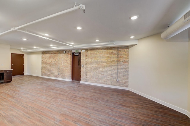 unfurnished living room with brick wall and wood-type flooring