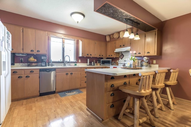 kitchen featuring pendant lighting, sink, a kitchen bar, kitchen peninsula, and stainless steel appliances