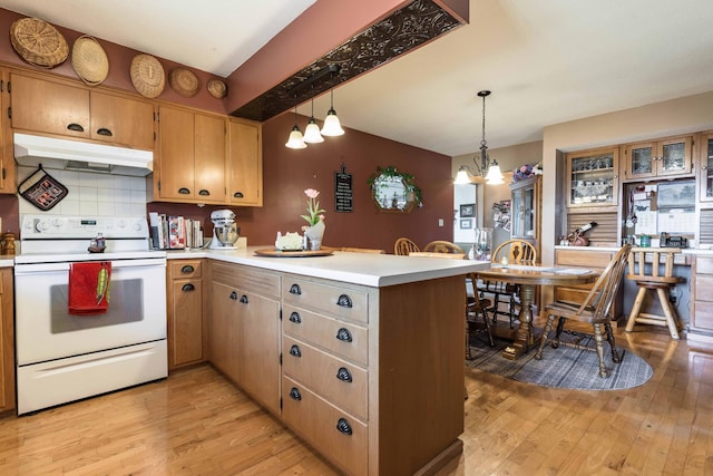 kitchen with kitchen peninsula, backsplash, electric stove, an inviting chandelier, and hanging light fixtures