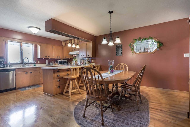 dining space featuring a textured ceiling, sink, a notable chandelier, and light hardwood / wood-style flooring