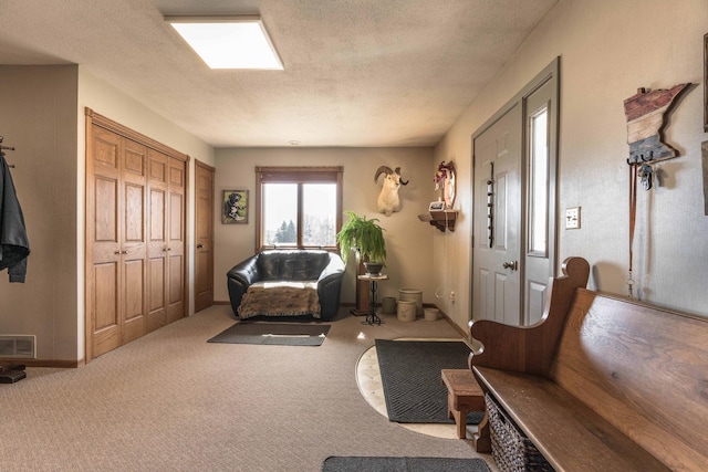 carpeted foyer entrance featuring a textured ceiling