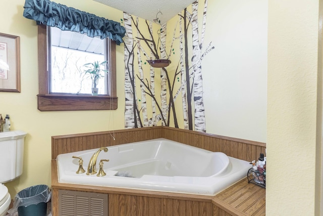 bathroom with a textured ceiling, toilet, and a bathing tub