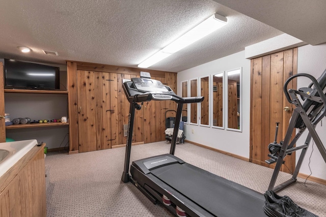 workout room featuring wood walls, carpet floors, and a textured ceiling