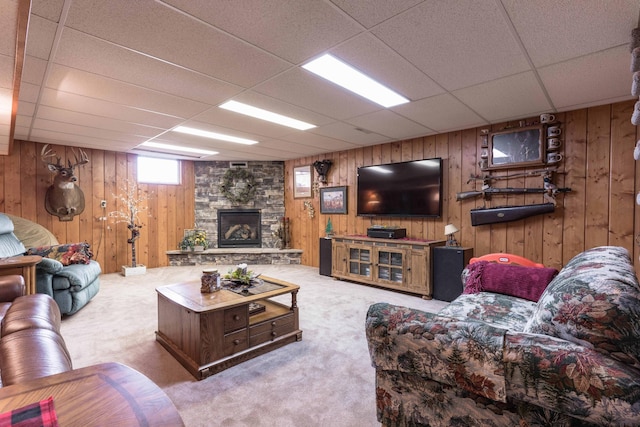 living room with a fireplace, light colored carpet, a drop ceiling, and wood walls