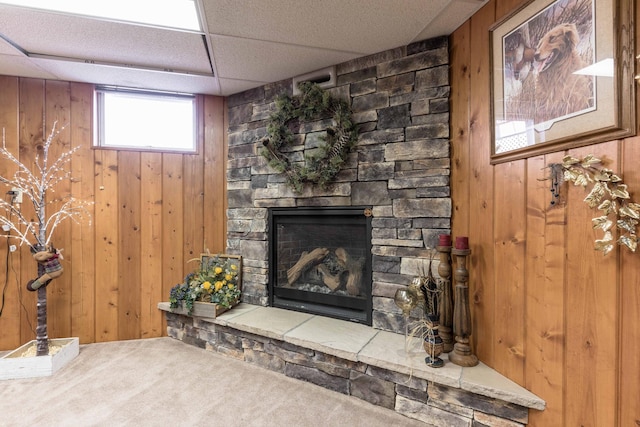 living room featuring a fireplace, a paneled ceiling, carpet floors, and wooden walls