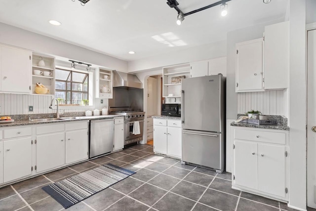 kitchen with white cabinetry, dark tile floors, sink, stainless steel appliances, and wall chimney range hood