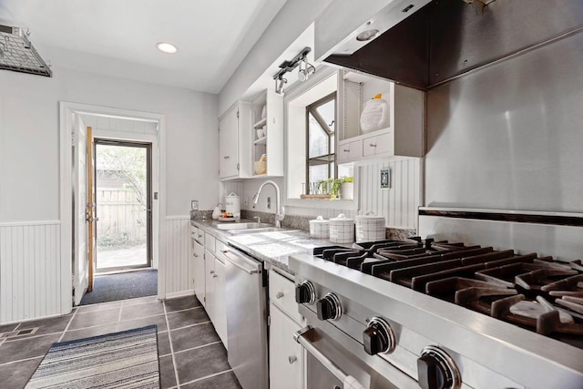 kitchen with appliances with stainless steel finishes, dark tile floors, white cabinetry, and sink