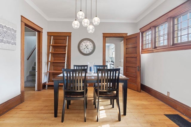 dining area featuring an inviting chandelier, light wood-type flooring, and ornamental molding