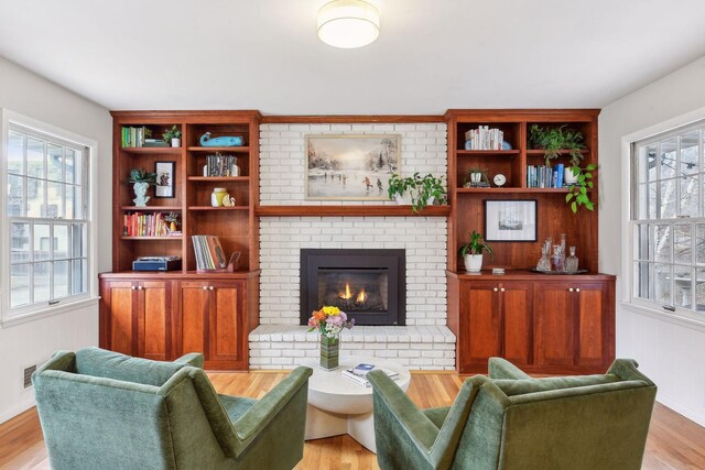 living room featuring light hardwood / wood-style flooring and a brick fireplace