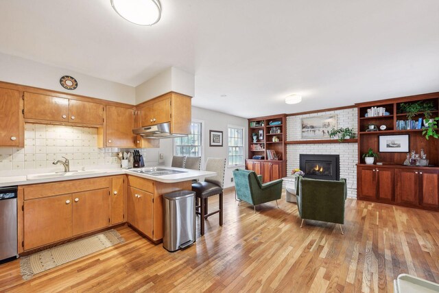 kitchen with light hardwood / wood-style floors, brick wall, a brick fireplace, sink, and tasteful backsplash