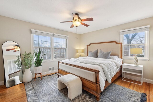 bedroom with hardwood / wood-style floors, ceiling fan, and multiple windows