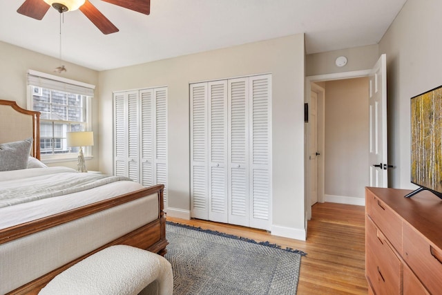 bedroom with ceiling fan, light wood-type flooring, and multiple closets