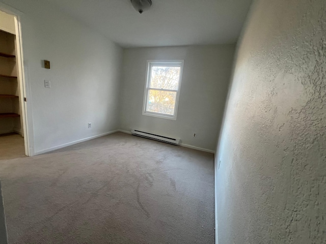 unfurnished room with light colored carpet and a baseboard heating unit