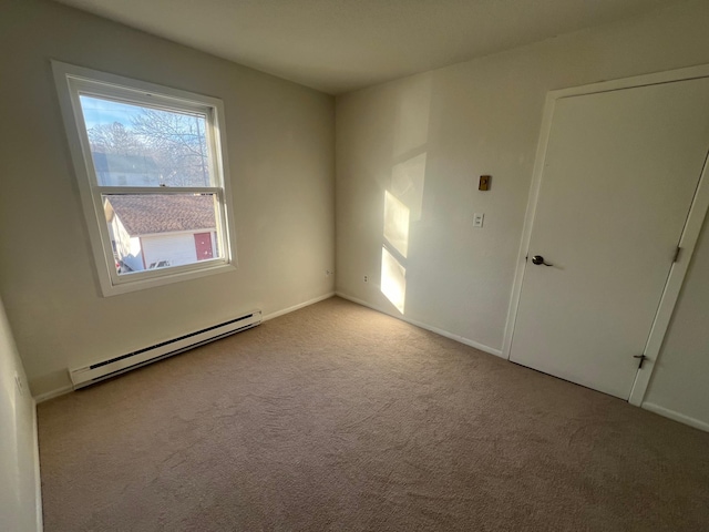 unfurnished room featuring light carpet and a baseboard heating unit