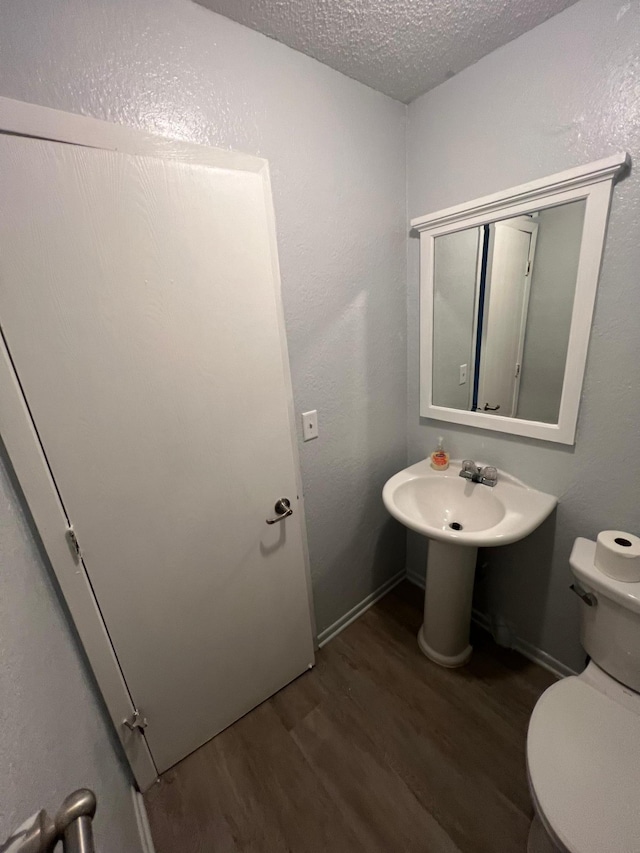 bathroom with hardwood / wood-style floors, toilet, and a textured ceiling