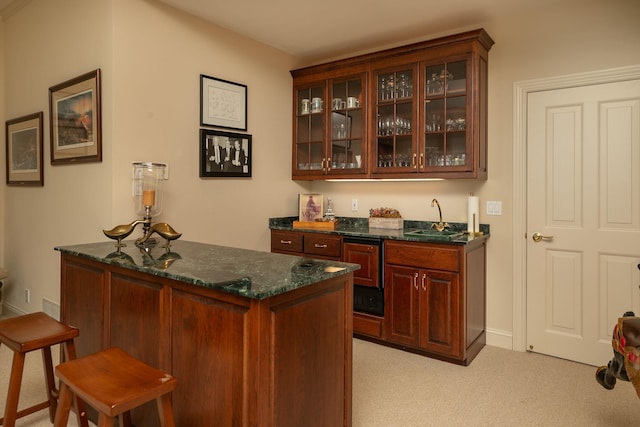 bar with light colored carpet, dark stone countertops, and sink