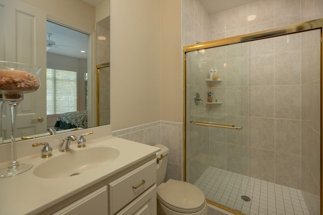 bathroom featuring ceiling fan, toilet, a shower with door, and vanity